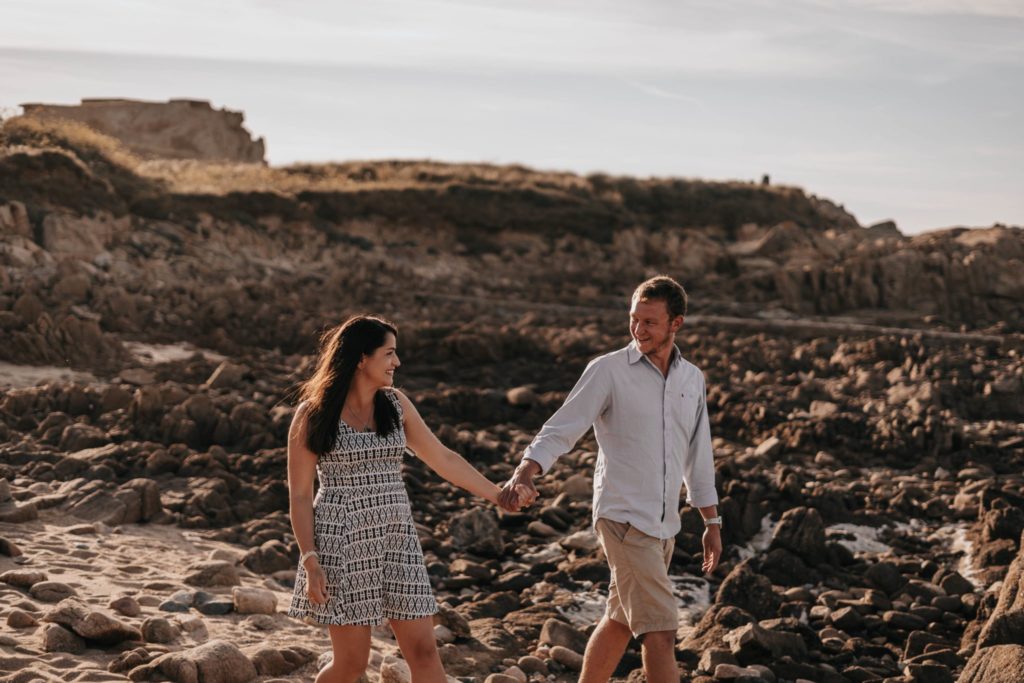 couple holding hands and walking on Grandes Rocques beach