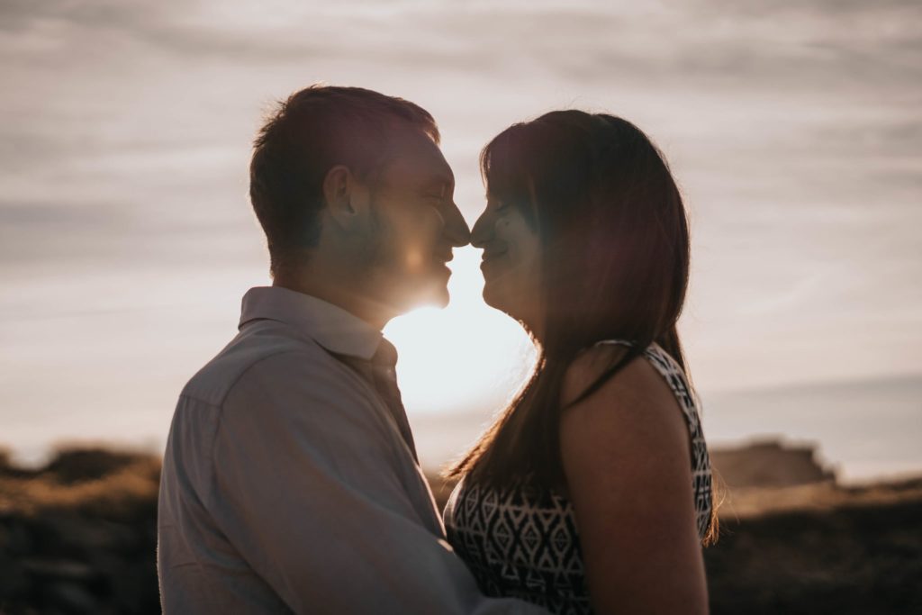 couple exchanging a kiss on the beach at sunset