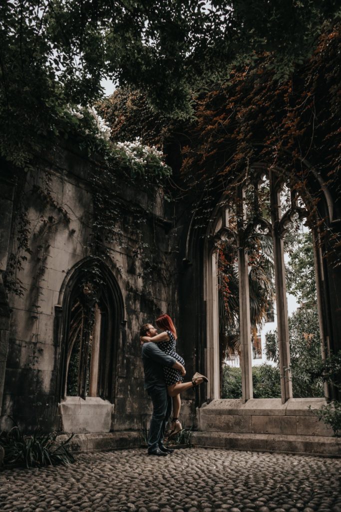 groom to be lifting his fiancee at their engagement session in St Dunstan in the East London