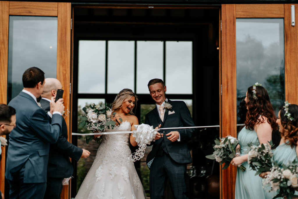 Bride and groom cutting ribbon at Villiers Barn's first ever wedding