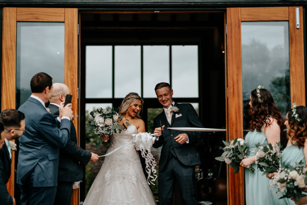 Bride and groom cutting ribbon at Villiers Barn's first ever wedding